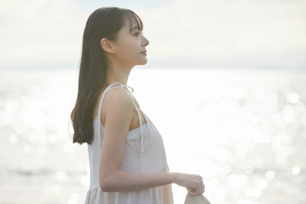 istock Young Asian woman strolling along the beach 2195228614