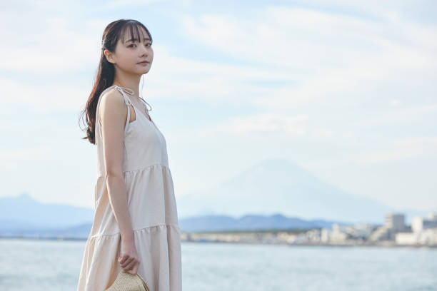 istock Young Asian woman strolling along the beach 2195228640