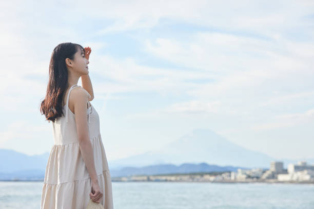 istock Young Asian woman strolling along the beach 2195228651