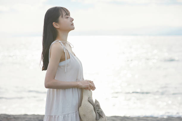 istock Young Asian woman strolling along the beach 2195228685