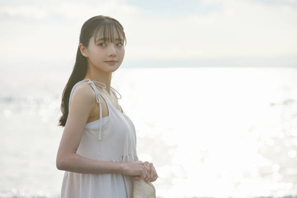 istock Young Asian woman strolling along the beach 2195228687