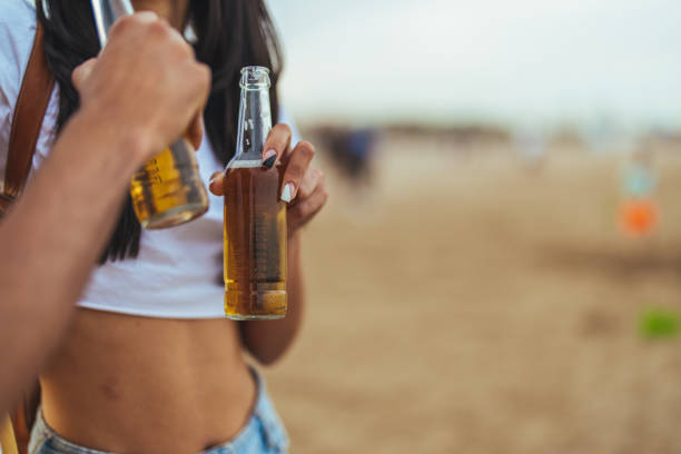 Two friends holding bottled beverages enjoy a casual day on the beach. The atmosphere is relaxing and warm, symbolizing leisure and summer vibes.