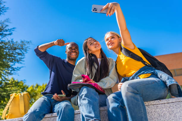 istock Multi-ethnic students taking selfie sitting outside the campus 2195230839