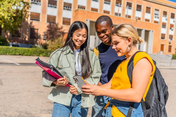 istock Students looking at the mobile phone standing in the campus 2195231020