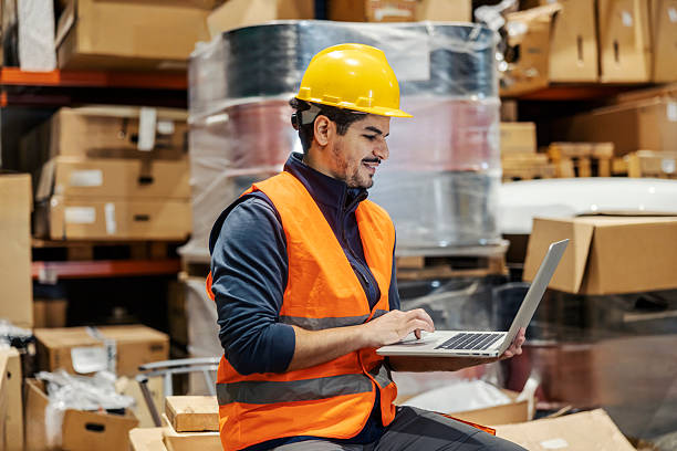 istock Happy multicultural warehouse worker tracking inventory on laptop. 2195231724