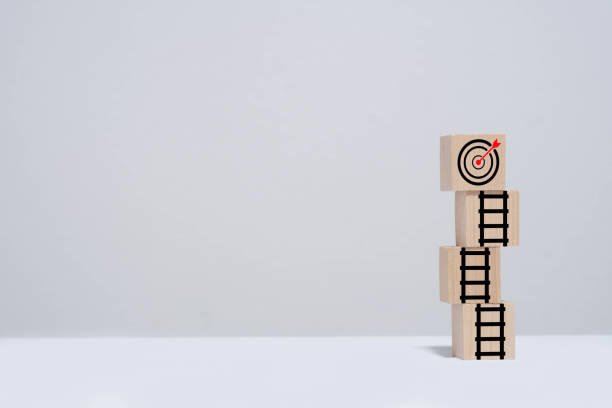 istock Wooden blocks with ladders leading to a target symbolize goal setting, growth, and achievement on a plain background. 2195232809