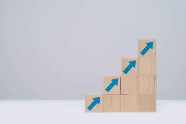 istock Wooden blocks stacked in ascending order with blue arrows, representing growth, progress, and success against a minimalistic background. 2195232810