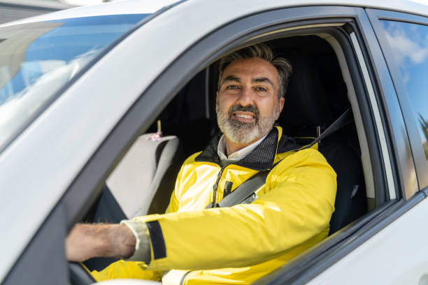 istock Smiling delivery man driving a car wearing yellow jacket 2195233273