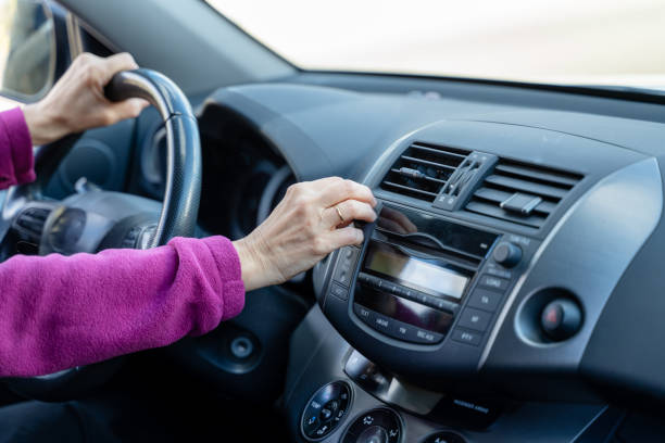 Senior woman driver inserting cd in car stereo while driving