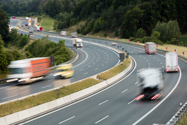 Highway in Bavaria, heavy goods transportation in Germany, trucks and cars speeding, aerial view.