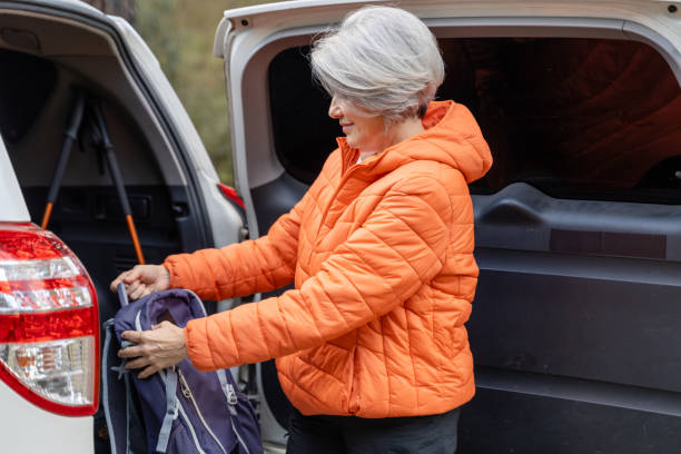 istock Senior woman putting backpack into car trunk before hiking 2195233894