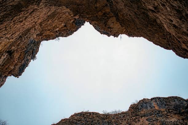 Looking up through a jagged rock canyon reveals bright blue skies above, evoking a sense of scale and geological wonder in Badami.