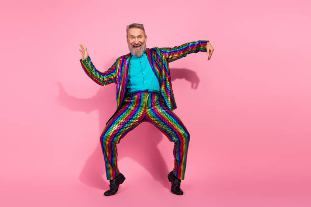 istock Eccentric elderly man in vibrant suit dancing on pink background for celebration or party 2195235227
