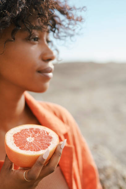 istock Woman Holding a Fresh Grapefruit Sliced In Half Under Bright Natural Light 2195235247
