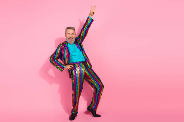 istock Charismatic mature man in vibrant striped suit posing confidently with cheerful expression on pink background 2195235250