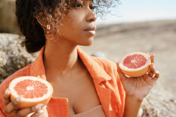 istock Young Woman Holding a Grapefruit Halves Against a Natural Backdrop in Bright Daylight 2195235267