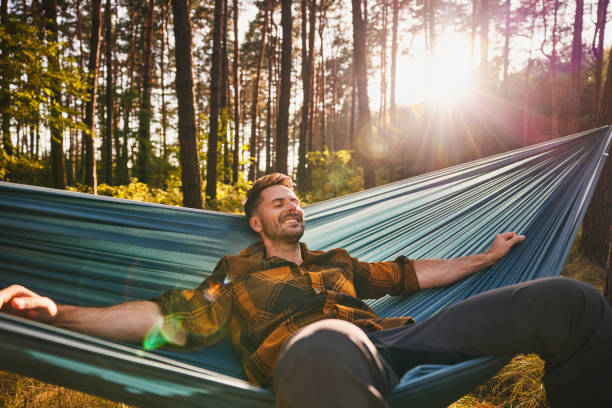istock Happy man lying in hammock enjoying forest nature 2195237515