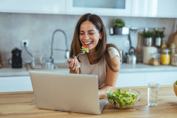 istock Woman Enjoys Healthy Salad While Video Calling in Modern Kitchen 2195238399