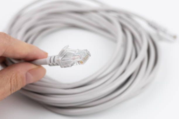 RJ-45 crimped red ethernet connector, unshielded twisted pair UTP internet cable end in hand, macro, detail, closeup. Individual cables visible. Cable crimping simple concept.