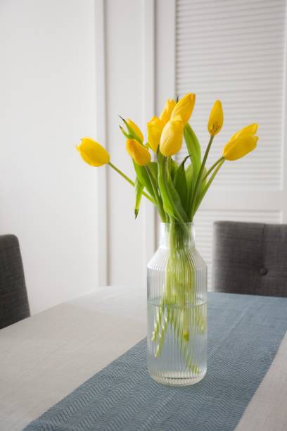istock Yellow tulips in a vase on a dining table. 2195240193