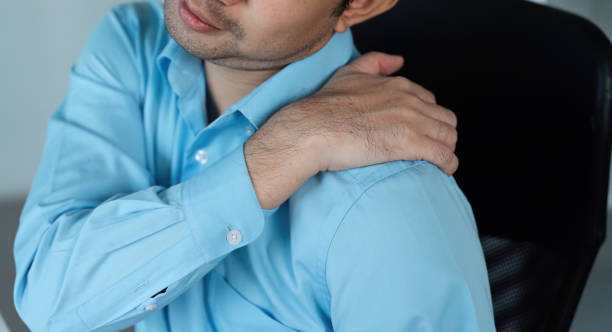 istock Young Businessman in Office Experiencing Aches and Pains While Working at Desk in Modern Corporate Environment 2195241555