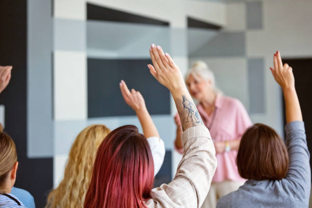 istock Back view one women raising hands during conference 2195244389