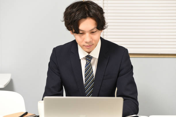istock An Asian man wearing a suit is operating a laptop while sitting at a desk 2195244714