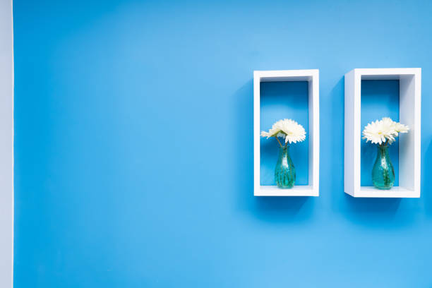 Vintage flower vase shelf on a blue wall.