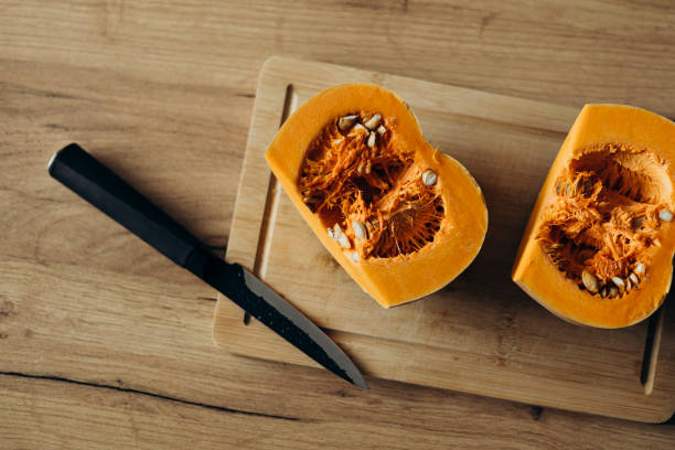 istock Orange ripe pumpkin cutted into two halves on a wooden table. 2195248312