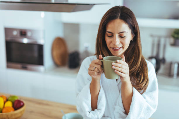 istock Woman in White Robe Enjoys Morning Coffee in Modern Kitchen 2195248416