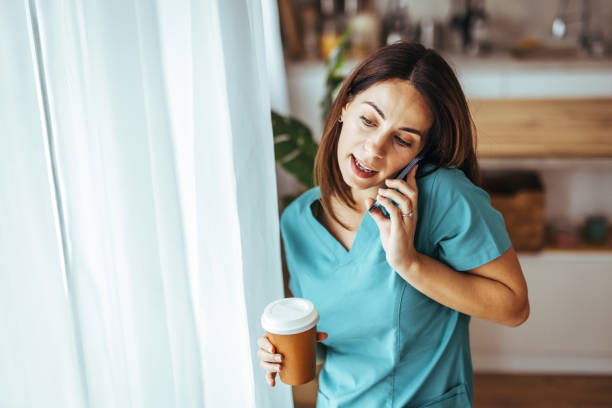 istock Female Nurse Talking On Phone While Holding Coffee Cup Indoors 2195248436