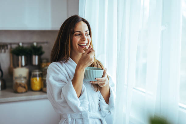 istock Happy Woman Enjoying Breakfast in a Sunlit Modern Kitchen Setting 2195248455