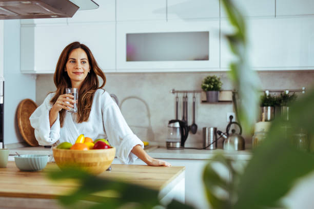 istock Woman Relaxing in Modern Kitchen with Fresh Fruit and Water 2195248456