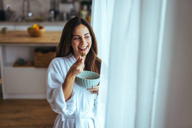 istock Woman Enjoying a Healthy Breakfast by the Kitchen Window in a Bathrobe 2195248467