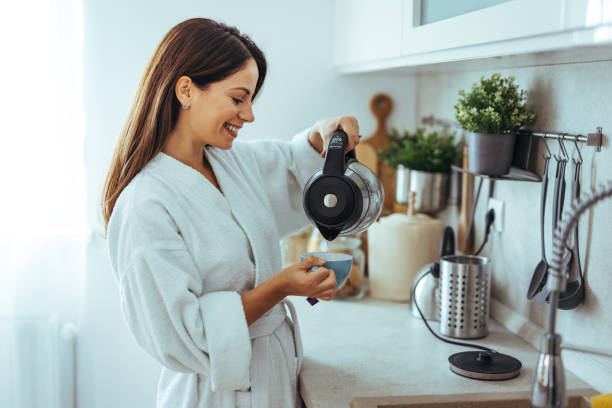 istock Woman Smiling While Pouring Coffee in Modern Kitchen Setting 2195248481