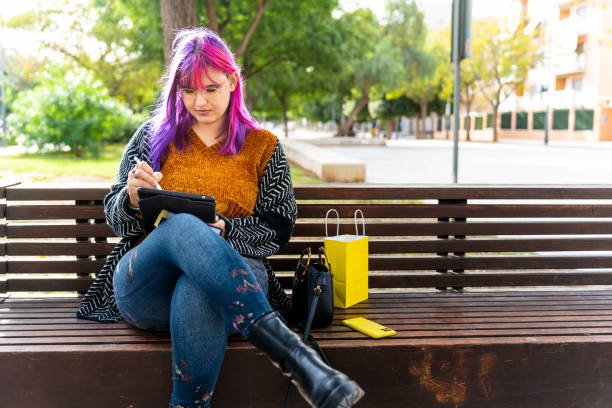 istock Body positive autistic woman using digital tablet on park bench 2195249596