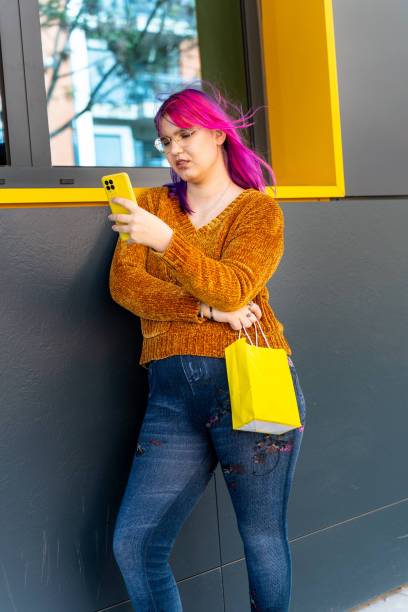 istock Body positive autistic shopper using smartphone and holding shopping bag 2195249648