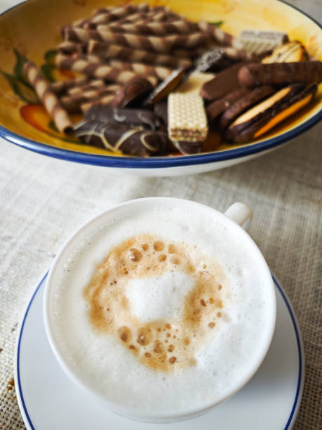 White cup of coffee next to a chocolate cake