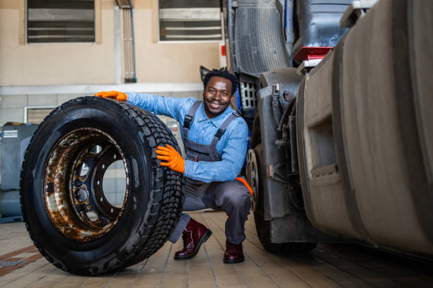 Mechanic replacing damaged truck tire and servicing the vehicle. Experienced mechanic changing damaged truck tyre inside repair shop.