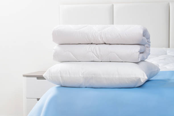 istock A bed with white pillows and a blanket, next to a bedside table with a lamp, daylight 2195252309