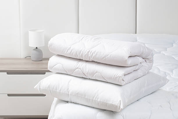 istock A bed with white pillows and a blanket, next to a bedside table with a lamp, daylight 2195252335