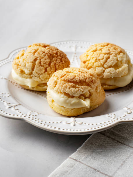 istock Chou pastry biscuits filled with whipped cream on grey background. Choux pastry. Homemade profiteroles with cream. Profiterole. Eclair. 2195253039