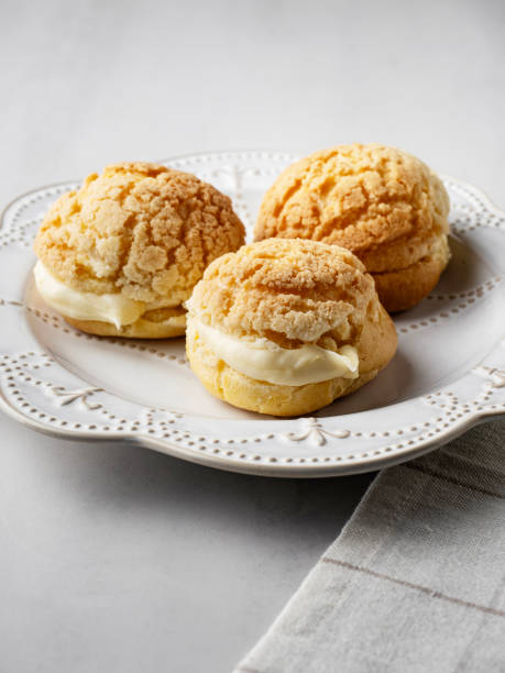 istock Chou pastry biscuits filled with whipped cream on grey background. Choux pastry. Homemade profiteroles with cream. Profiterole. Eclair. 2195253090