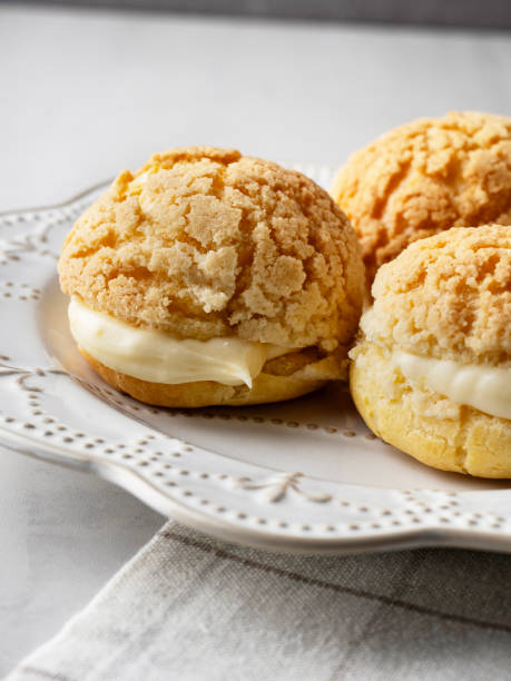 istock Chou pastry biscuits filled with whipped cream on grey background. Choux pastry. Homemade profiteroles with cream. Profiterole. Eclair. 2195253239