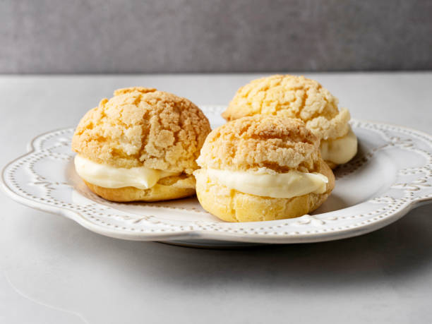 istock Chou pastry biscuits filled with whipped cream on grey background. Choux pastry. Homemade profiteroles with cream. Profiterole. Eclair. 2195253302