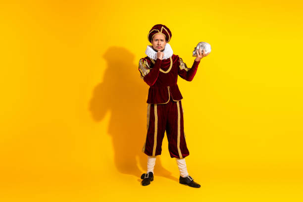 Actor in royal costume posing with dramatic expression on vibrant yellow background suggestive of historical and theatrical parody themes.