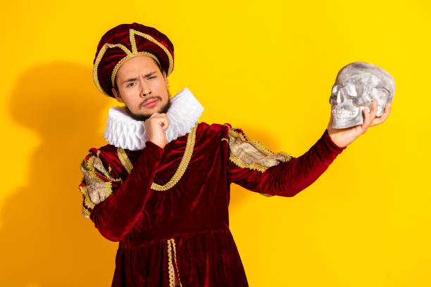 istock Young Man as Medieval Aristocrat Posing Dramatically With Skull Against a Bright Yellow Background 2195253716