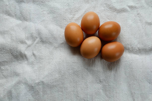 istock A group of five brown eggs arranged on a textured white cloth. 2195253862