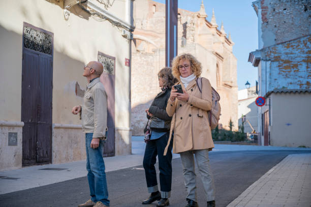 istock Three senior adults exploring a historic European town, with one checking a smartphone, another admiring architectural details, and a third observing the surroundings on a sunny day 2195254223