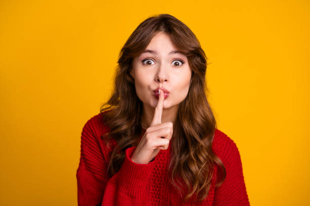 istock Young woman making hush gesture with finger on lips, posing against bright yellow background 2195254304